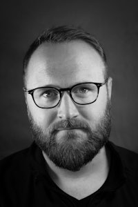 a black and white photo of a man with glasses and a beard